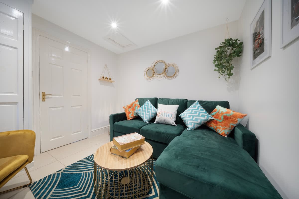 Green corner sofa and patterned rug in the one-bedroom Esho Stays flat near Gloucestershire Royal Hospital