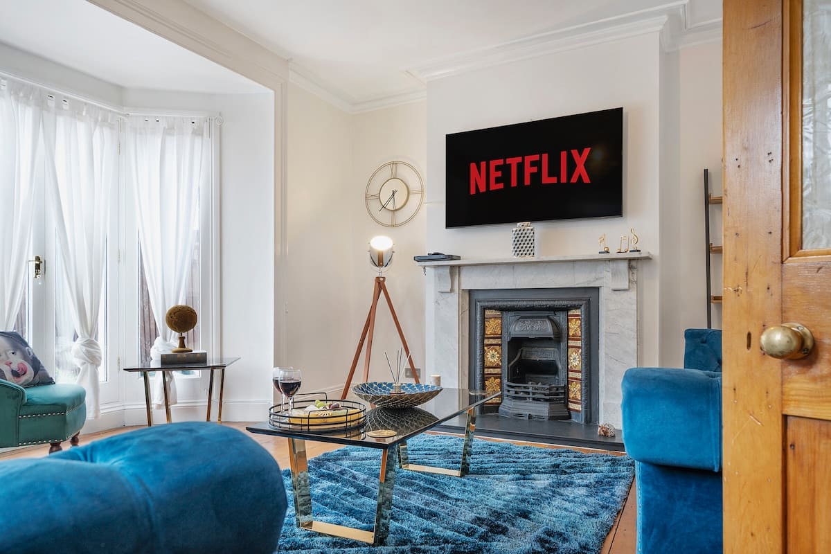 Living room with blue sofas and a period fireplace in the Esho Stays four-bedroom contractor house near Gloucestershire Royal Hospital