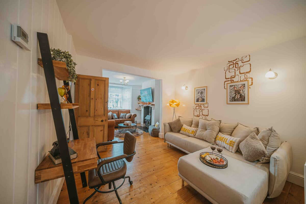 Living room with a desk, sofa and wooden floors in the two-bedroom Esho Stays house in Cirencester
