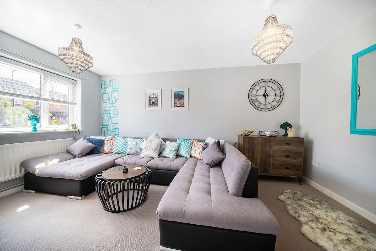 Large grey corner sofa and chandeliers in the three-bedroom Esho Stays house near Coventry Canal Basin