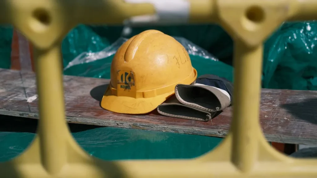 A yellow hard hat and work gloves resting on a plank at a building site, ready for a crew that needs contractor accommodation