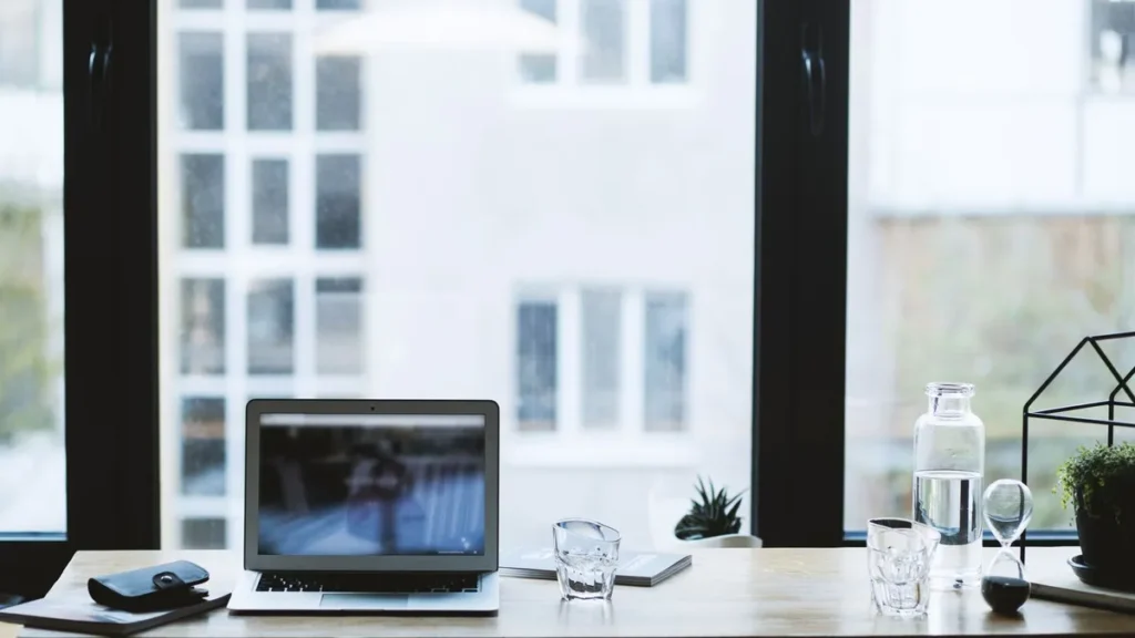 A laptop on a desk by a bright window, set up for a work trip in business accommodation in Gloucester